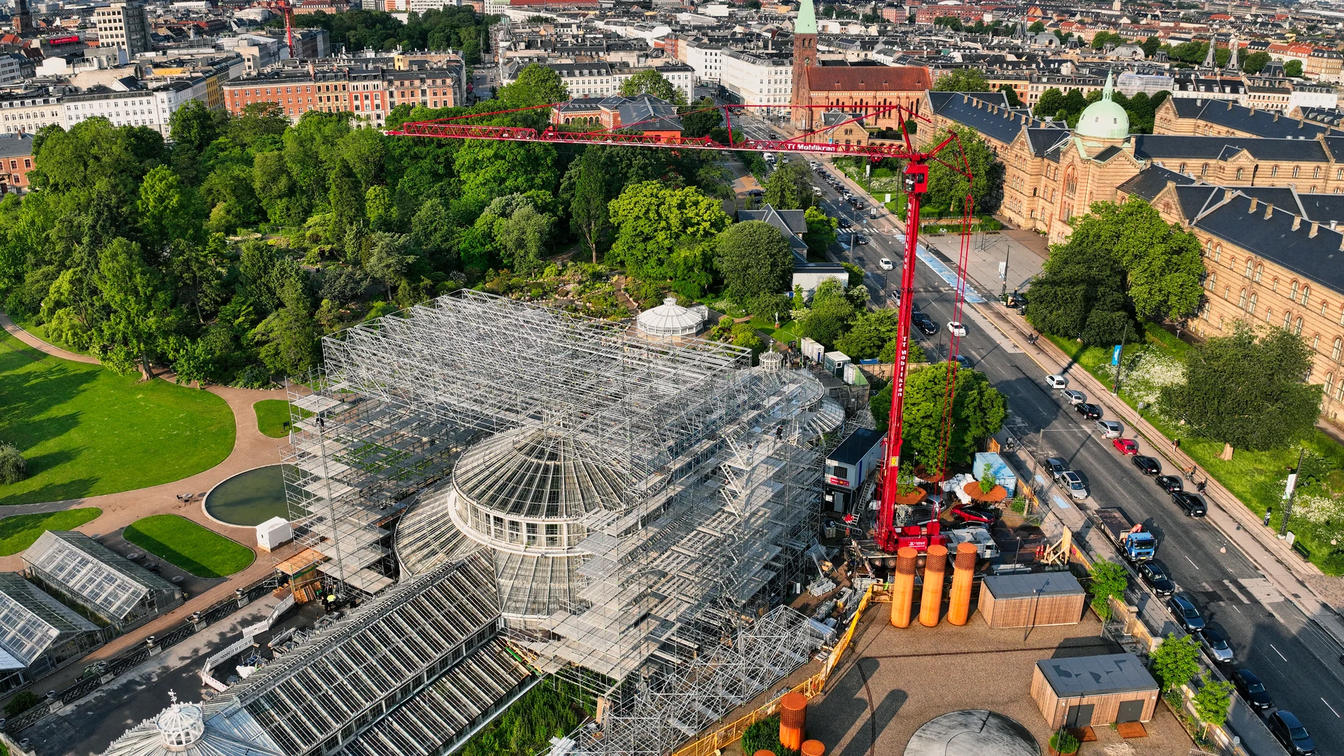 Dronefoto af Palmehuset med stillads, kran og Københavns bymiljø i baggrunden.