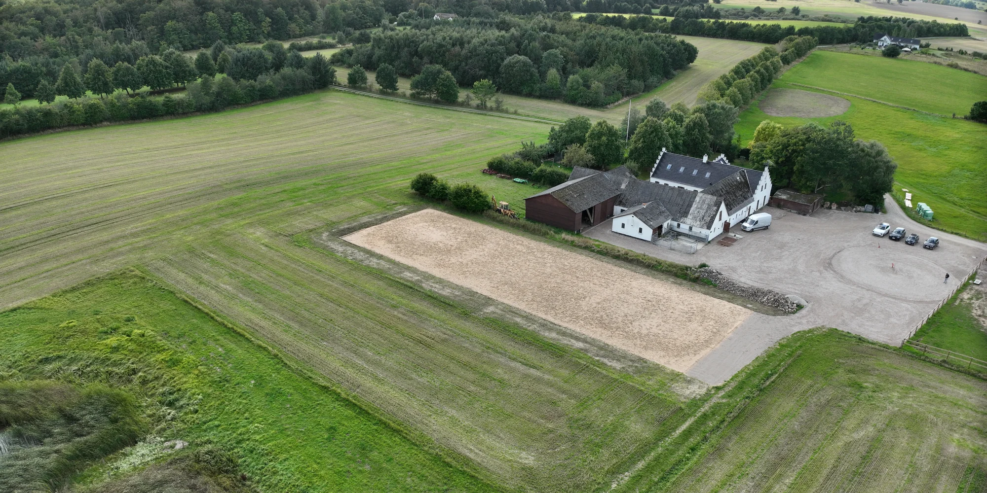 Dronefoto af det færdige anlægsprojekt ved Markildevej med ridebane og gårdsplads.